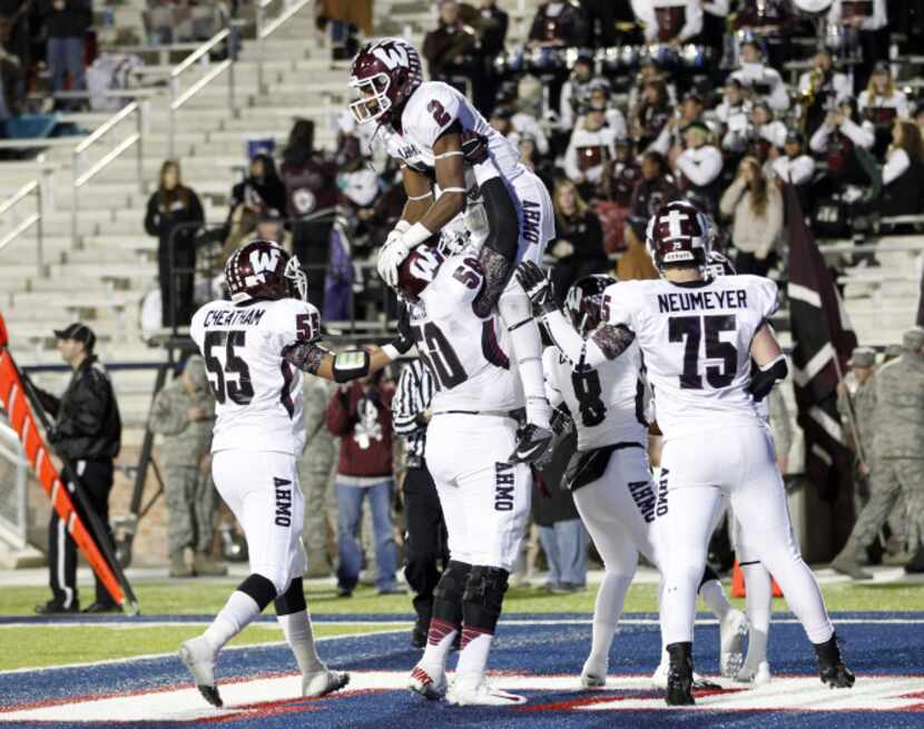 Wylie offensive lineman Laurent Njiki (50) lifts wide receiver Kameron Kelly (2) in the air...