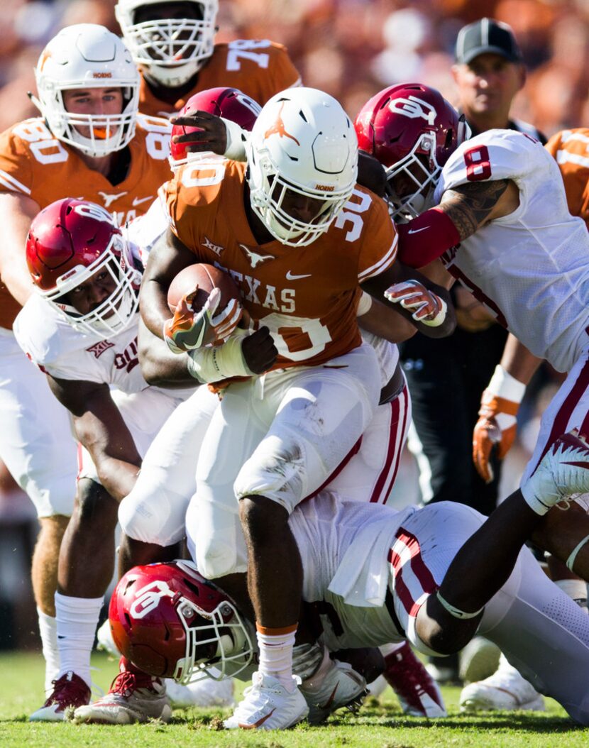 Texas Longhorns running back Toneil Carter (30) is tackled by Oklahoma Sooners defenders...