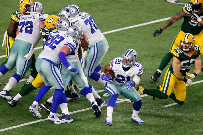 Dallas Cowboys running back Ezekiel Elliott (21) spins out of an attempted tackle by Green...