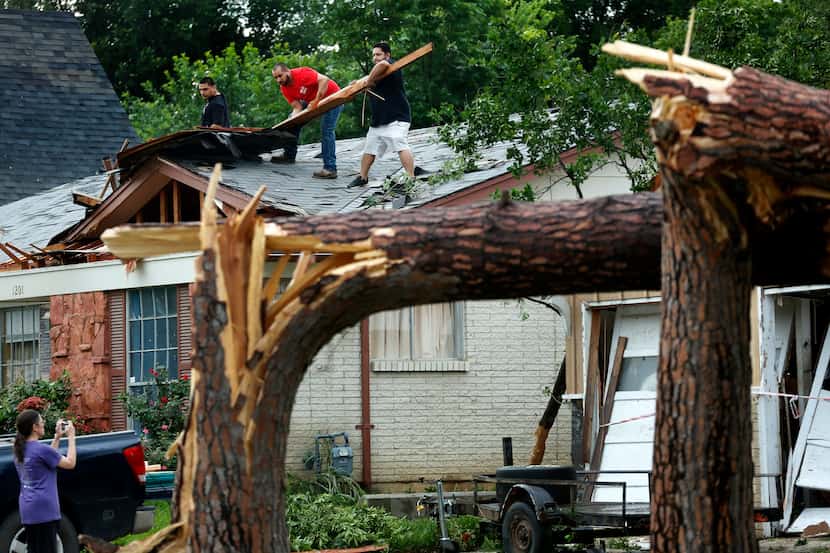 Volunteers help residents along Andrews St. clear roof debris in north Arlington after large...