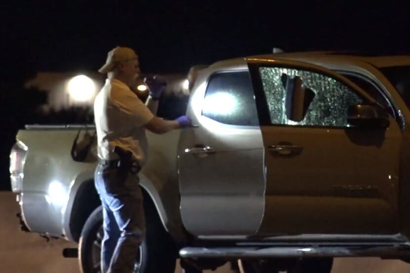 A Fort Worth police investigator looks over a truck with its passenger-side window shot out...