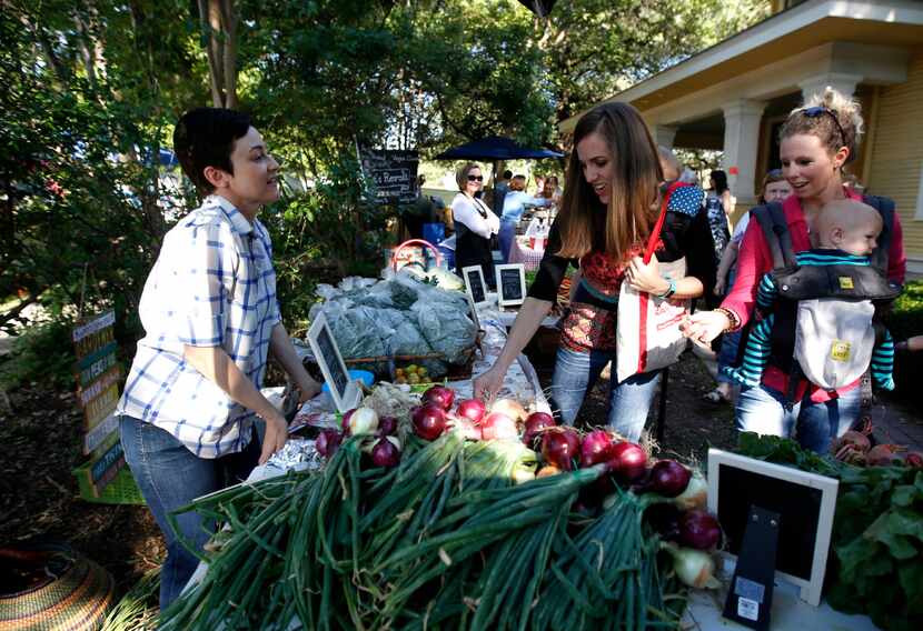 Megan Neubauer of Pure Land Organic (left) sells produce to Liz Lamb and Amanda Phillips,...