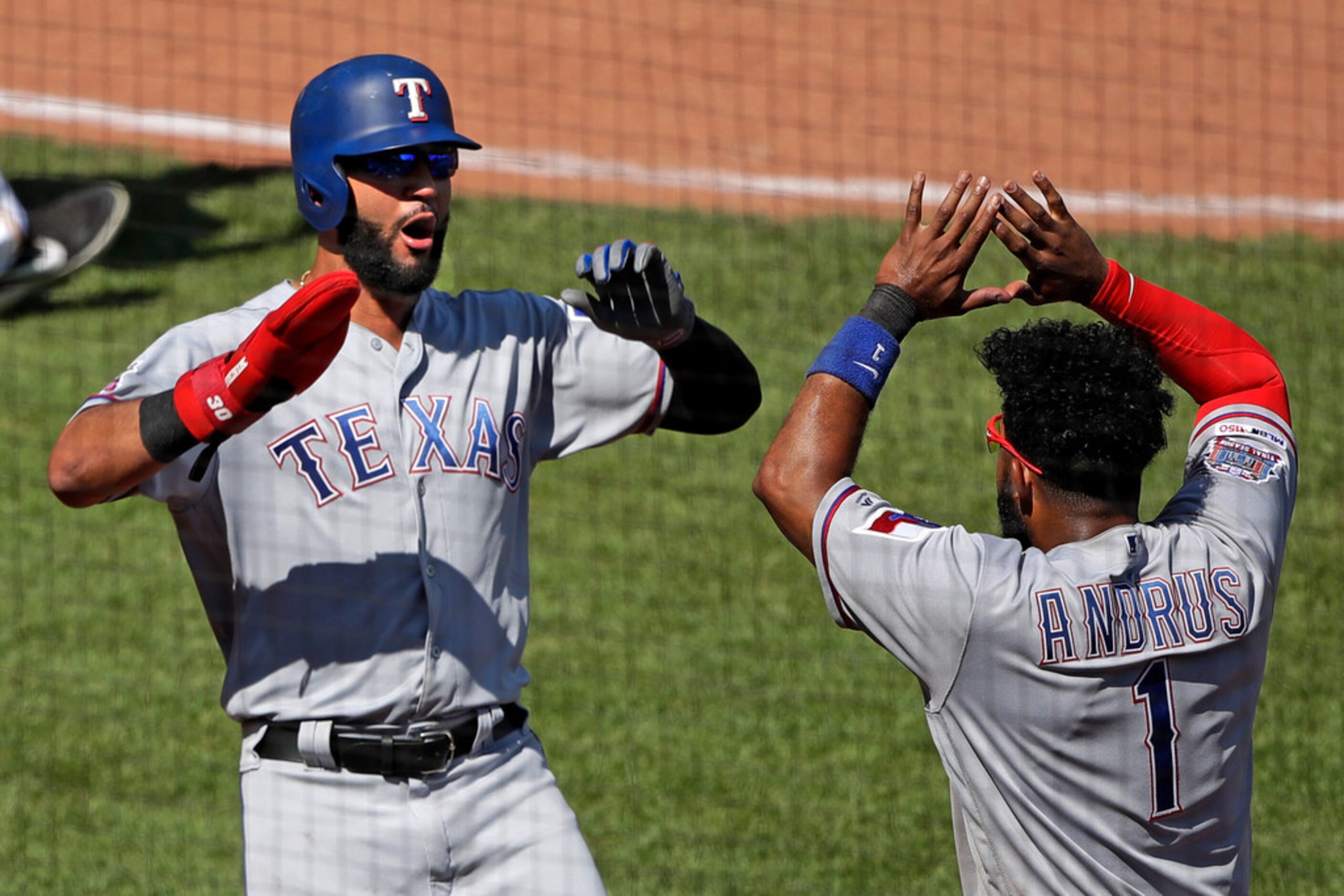 Texas Rangers' Nomar Mazara, left, celebrates with Elvis Andrus (1) after scoring on a...