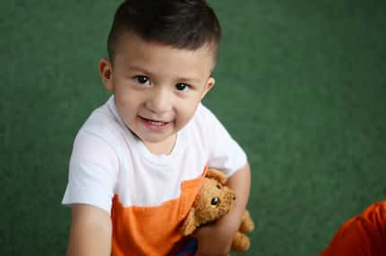 Young boy holding a stuffed animal while playing