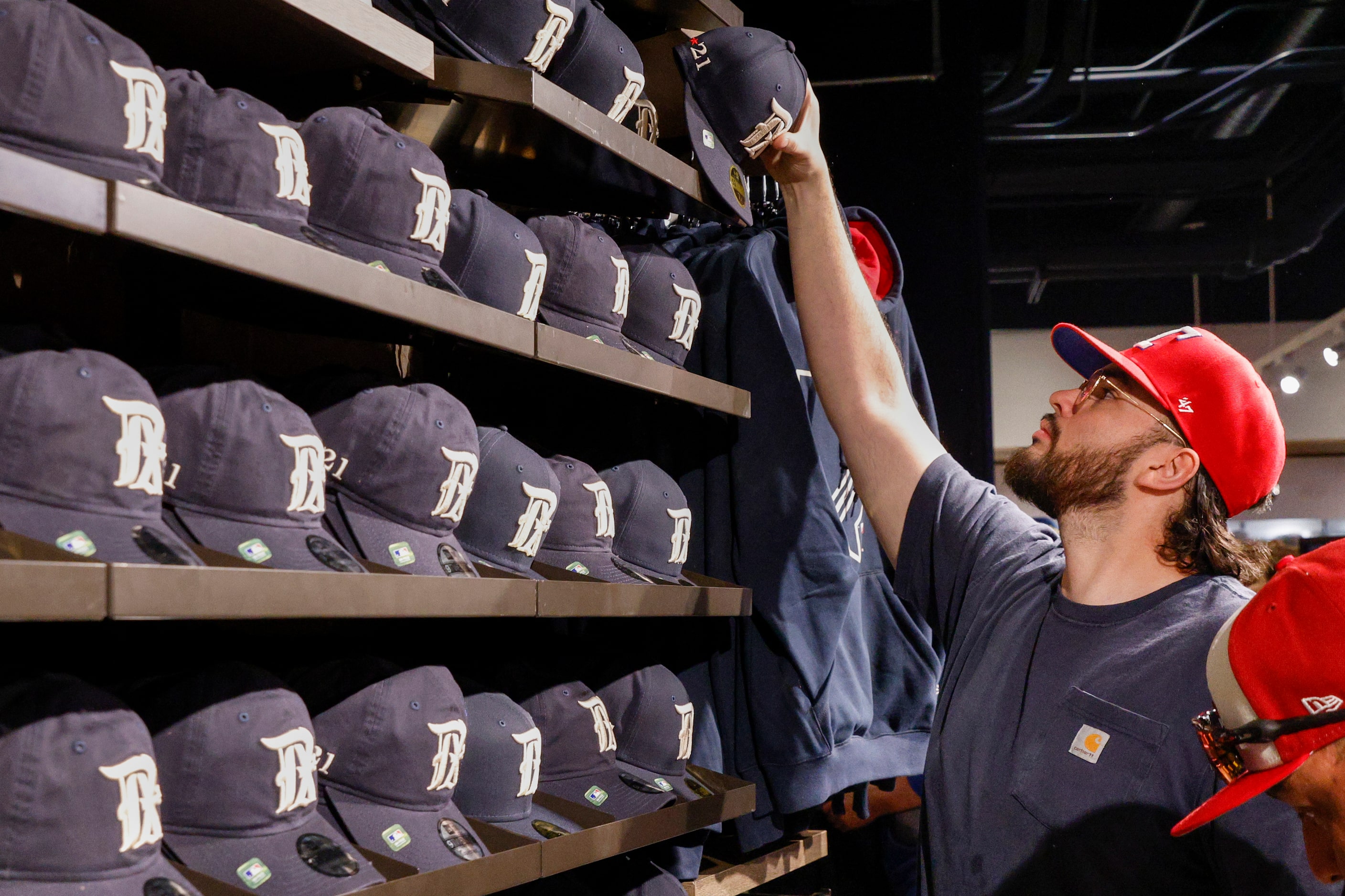 Philip Argumaniz reaches for a new Texas Rangers City Connect hat at Globe Life Field on...