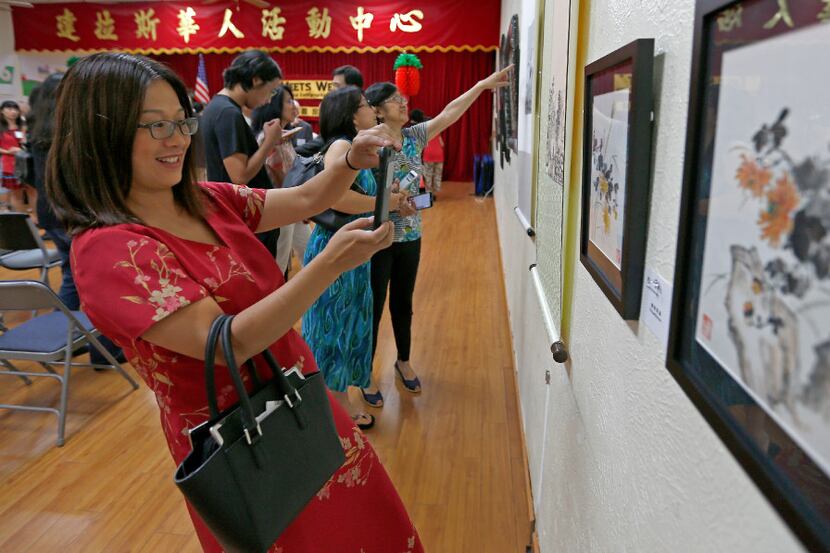 Heather Wang uses her cell phone to photograph one of artworks during the East Meets West:...