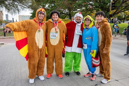 Five people in various costumes and wearing race bibs pose together.