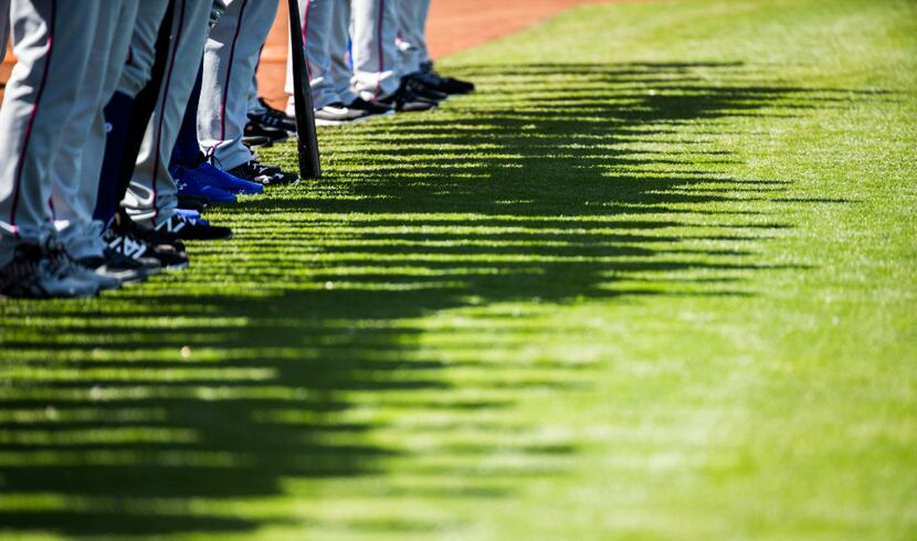 FILE - Rangers players' shadows appear on the grass as they line up for the national anthem...