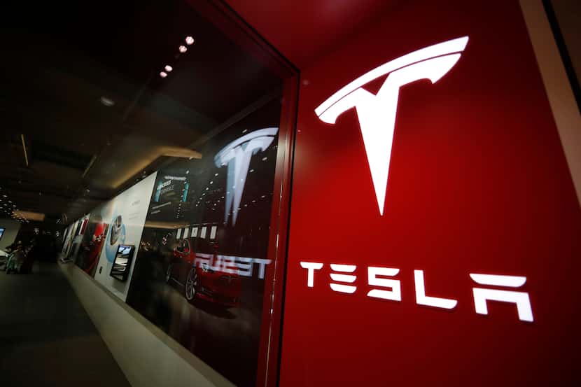 Un letrero con el logotipo de la empresa Tesla luce afuera de una tienda de estos vehículos...
