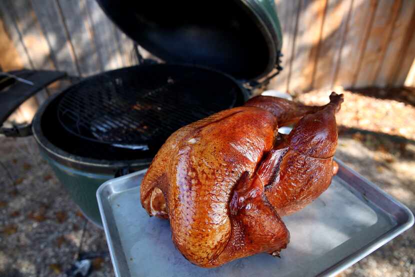 A turkey is removed from a Big Green Egg smoker.