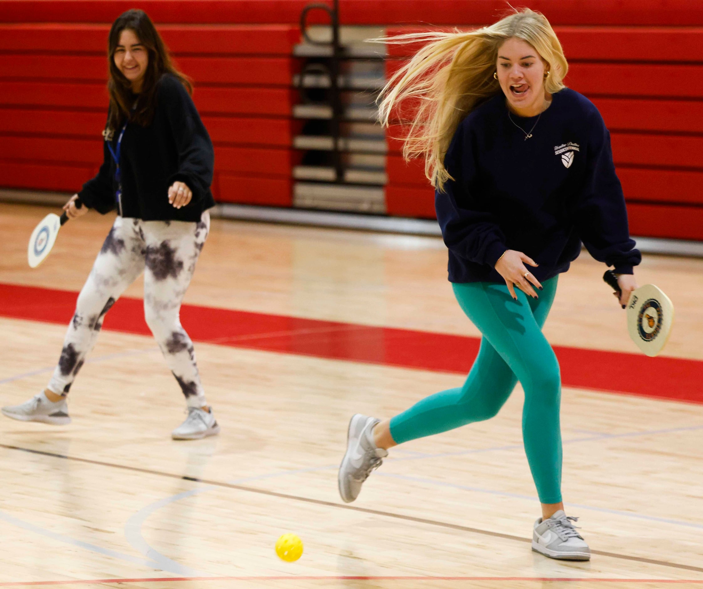 Sofia Harfuch (left) watches as Anne Marie Long attempts to hit while playing pickle ball...