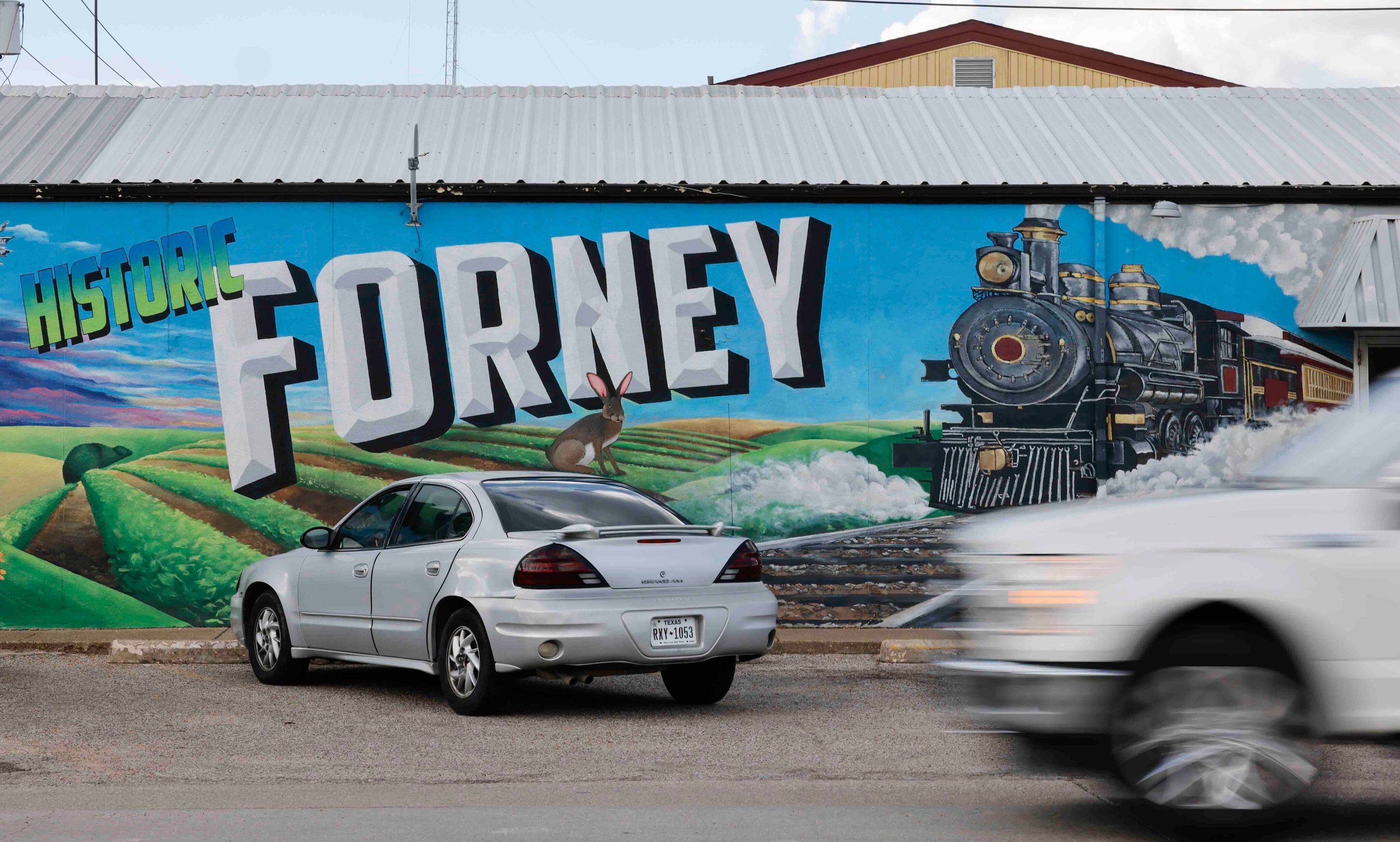 Traffic passes by a mural in downtown Forney.