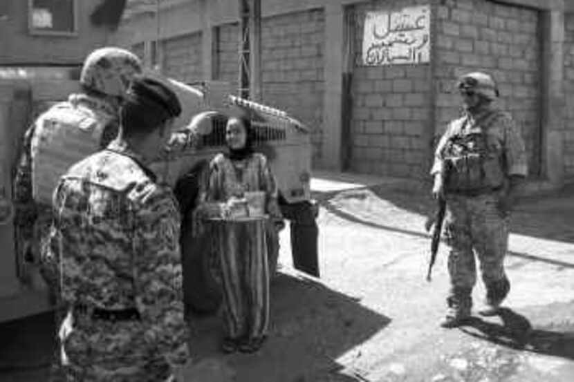 Iraqi soldiers and federal police officials are offered tea by a resident in Mosul as they...