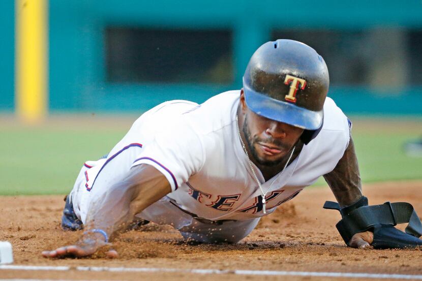 Texas Rangers left fielder Delino DeShields (3) dives back to first on a pickoff attempt in...