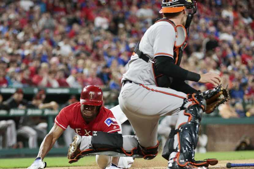 Texas Rangers' Delino DeShields, left, dives and scores ahead of the tag by Baltimore...