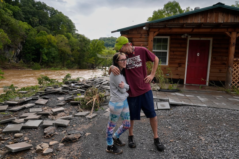 FILE - Jonah Wark, right, kisses his wife Sara Martin outside their flood-damaged home on...