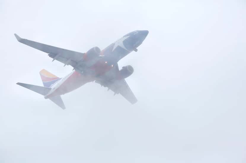 A Southwest Airlines jet cut through the low cloud bank in downtown Dallas on its way to...