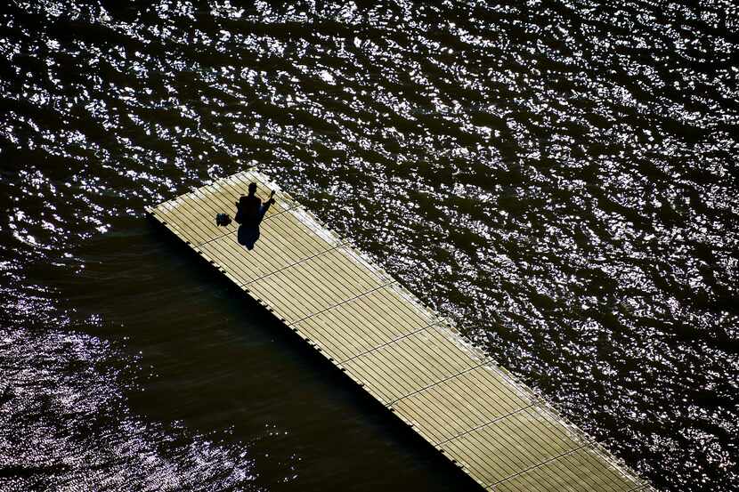 Aerial view of a solitary man sitting on a boat dock at White Rock Lake in Dallas on March...