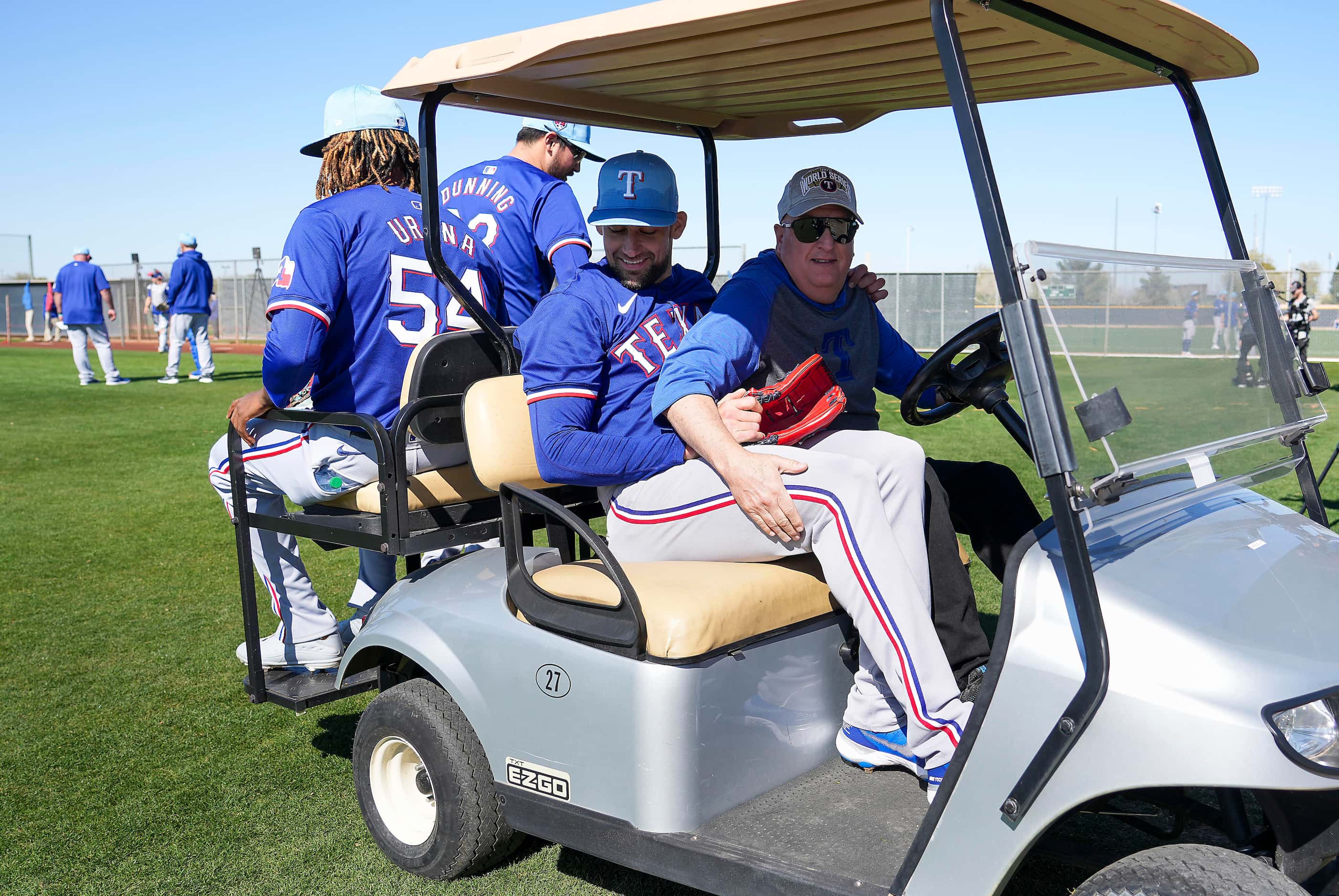 Texas Rangers pitcher Nathan Eovaldi (17) piles into a golf cart driven by Blake Miller, the...