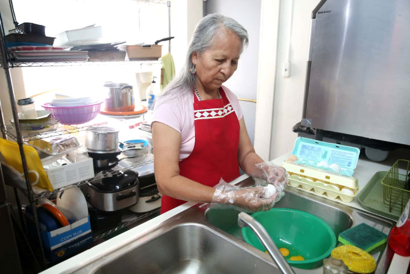 Pauline LongFox cracks eggs to combine with a wild onion dish in the kitchen at Dallas...