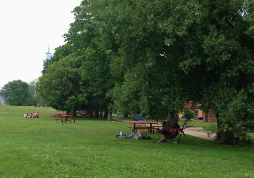 Adirondack chairs, picnic tables, and hammocks are tucked under the trees around the ...