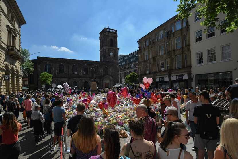 Flowers and balloons are left in Saint Ann's Square in tribute to those killed in an...