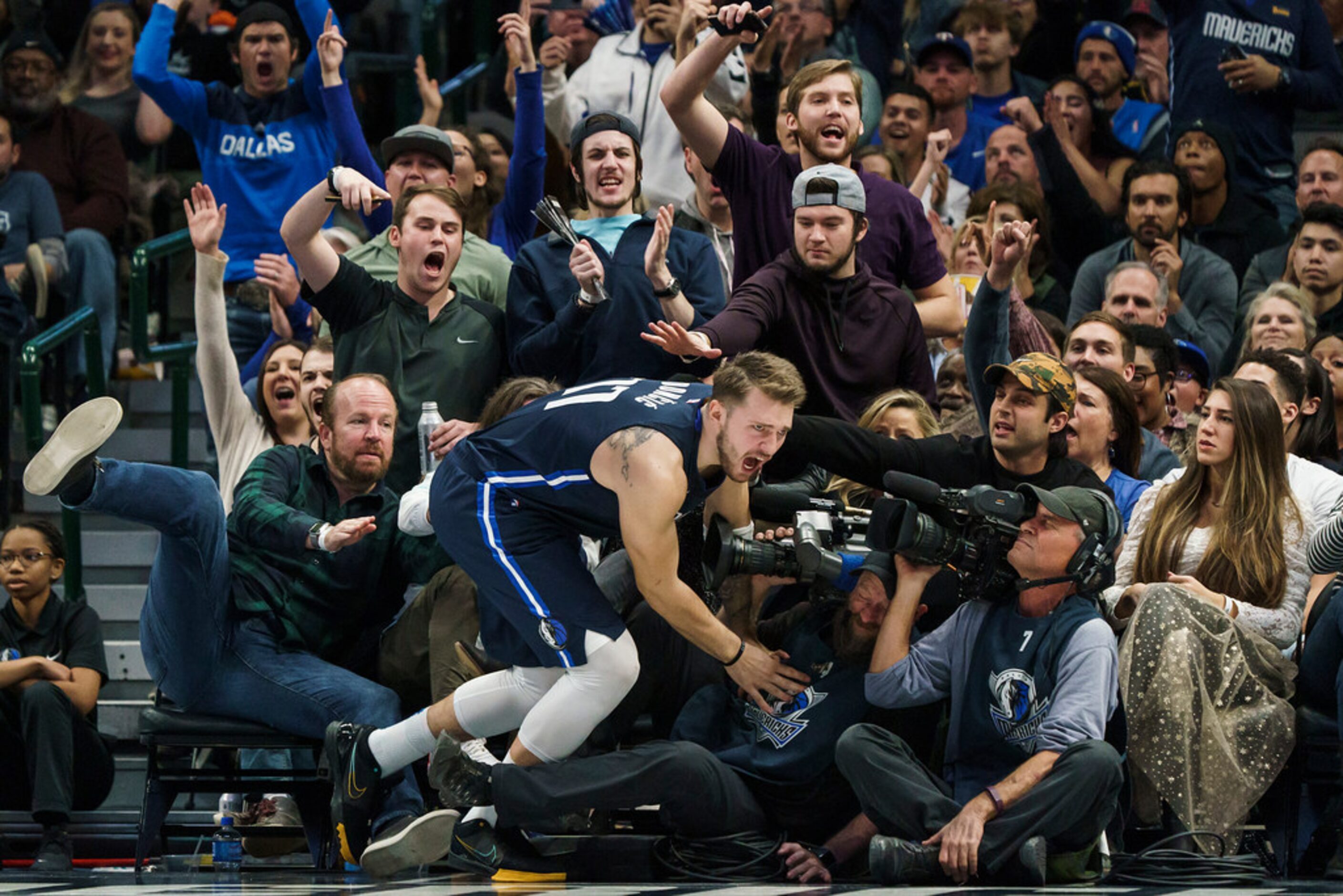 Dallas Mavericks guard Luka Doncic tumbles into the seats after making a shot during the...