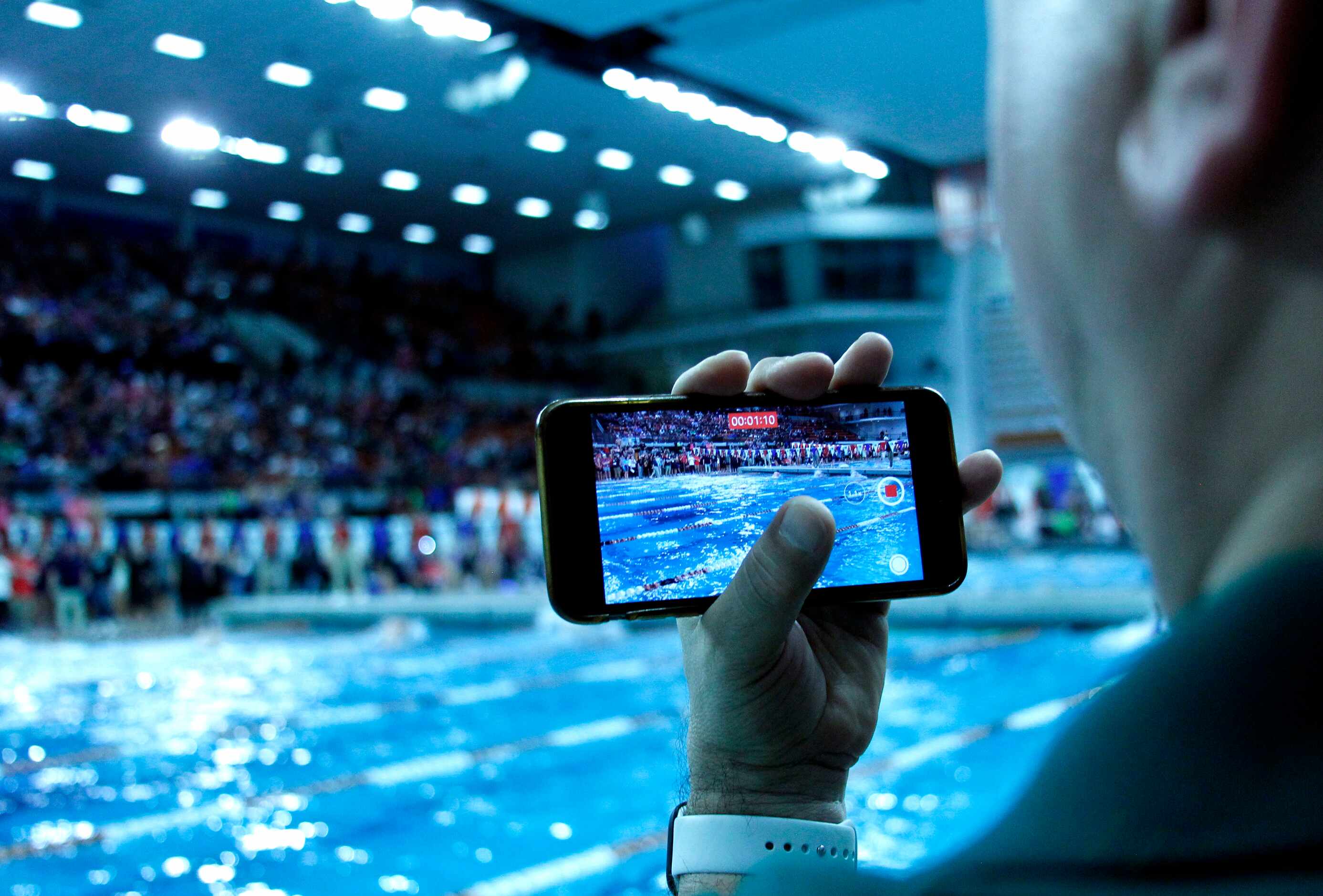A fan poolside records a race during 6A competition. The first day of the UIL state swimming...