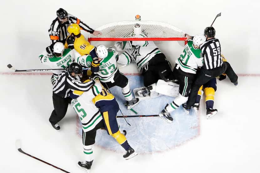 Dallas Stars goaltender Ben Bishop takes refuge in the net as players fight during the first...