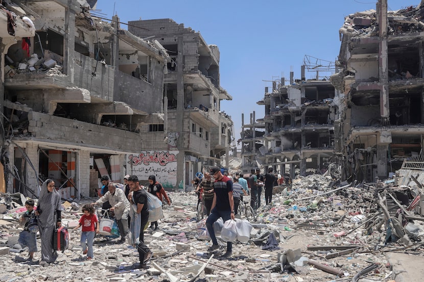 Palestinians walk through the destruction in the wake of an Israeli air and ground offensive...