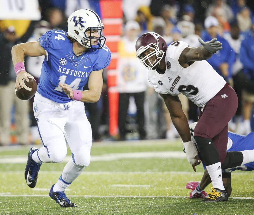 Kentucky quarterback Patrick Towles scrambles from the grasp of Eastern Kentucky defensive...