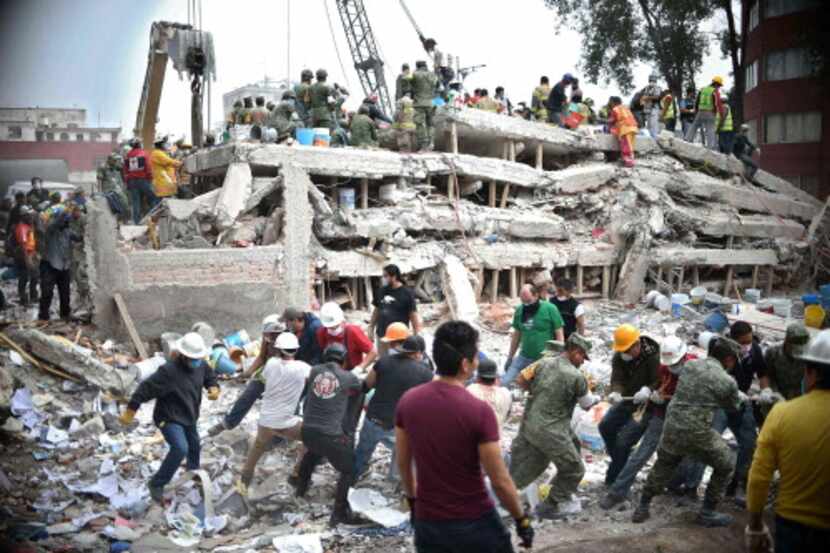 Rescatistas, soldados y voluntarios buscan sobrevivientes entre los escombros de un edificio...