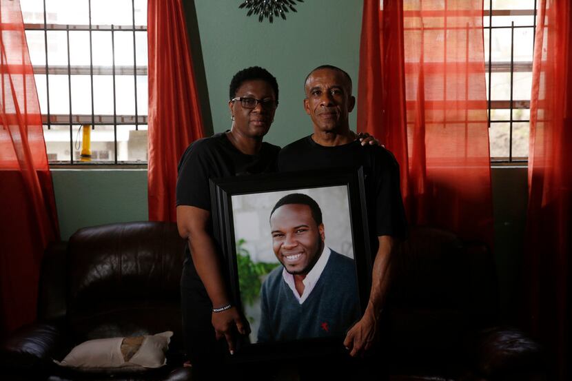 Allison and Bertrum Jean hold a photo of their son Botham Jean at their home in Castries,...