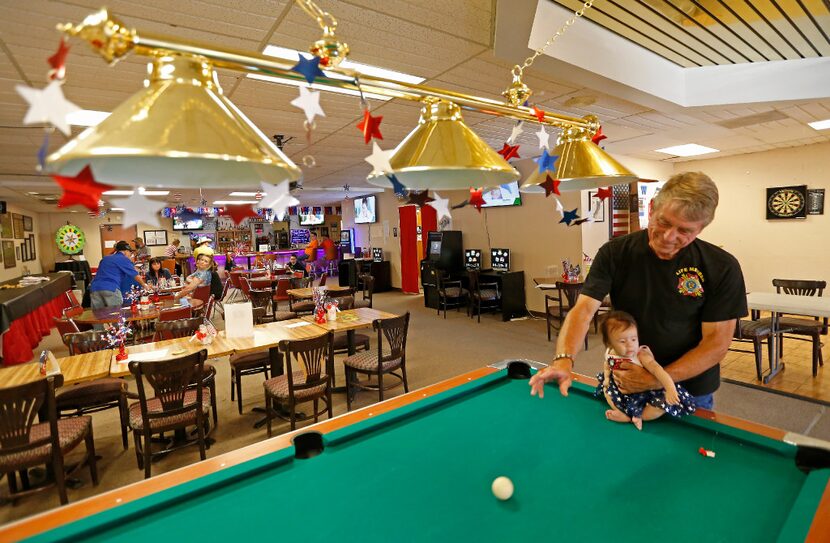 Post commander Rick Bennett (right) holds his 4-month-old grand daughter Lucy Gomez at VFW...