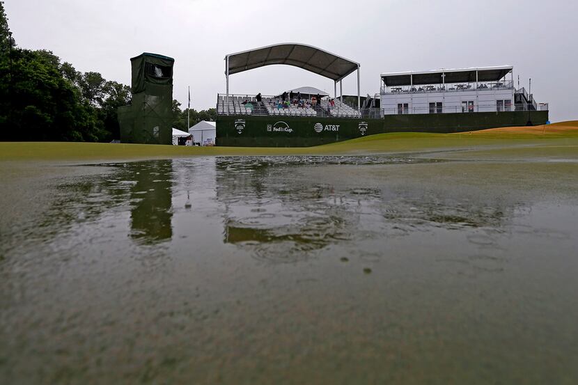 The 9th green is flooded with water as spectators sit in the stand during a weather delay of...