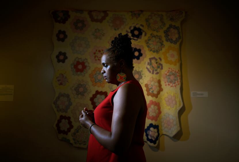 Anyika McMillan-Herod poses in front of a "Flower Garden Quilt" by a Central Texas slave...
