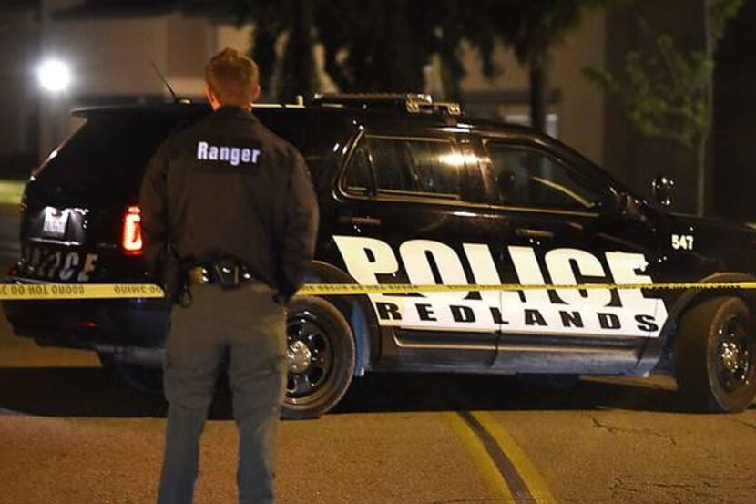  An officer stands guard at the police perimeter early Thursday in a Redlands, Calif.,...