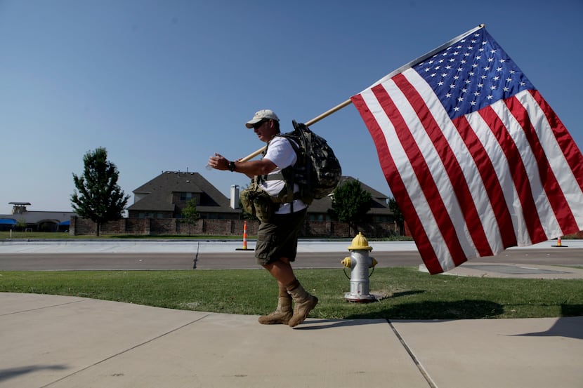 Brian Falcon walks with an American flag during the 10 mile hump, a military term for a...