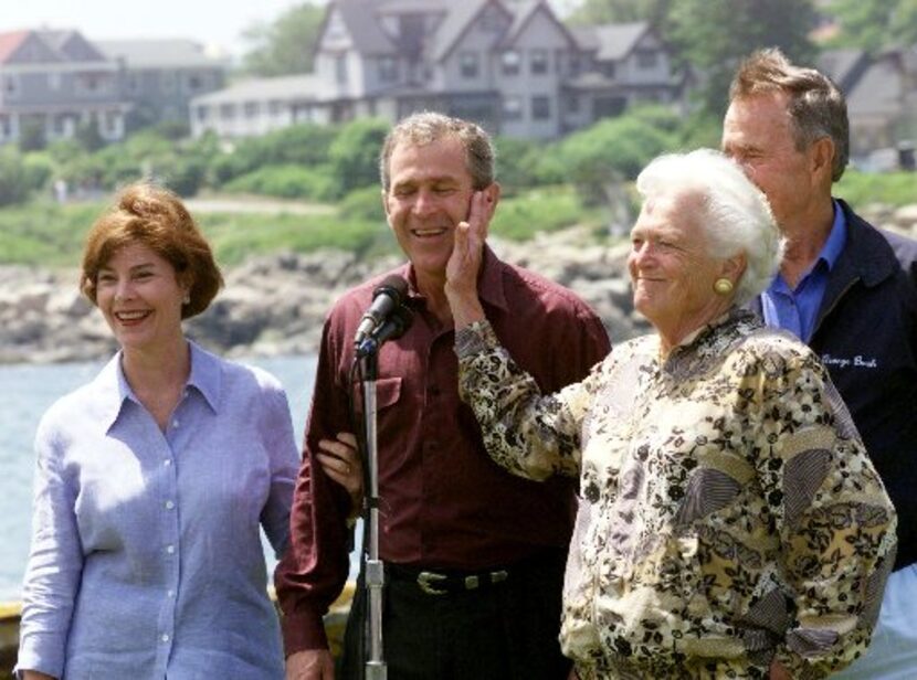 Barbara Bush (R) playfully slaps his son, Texas Governor George W. Bush, during a photo op...