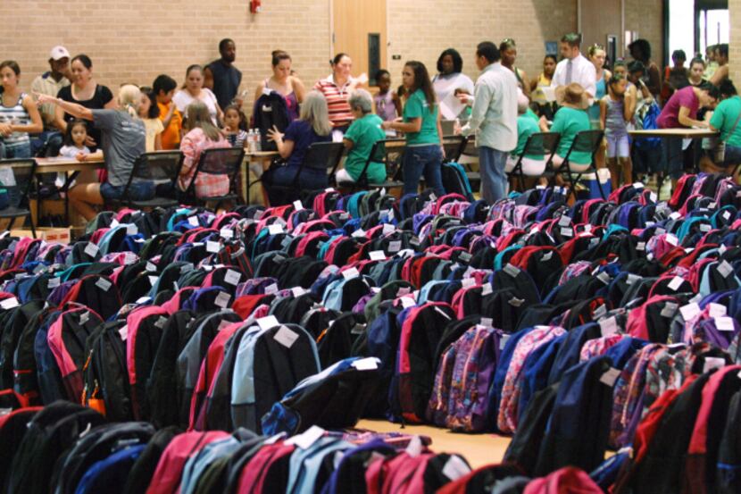 Hundreds of backpacks sits in rows at the annual Apple Tree Project, which distributes...