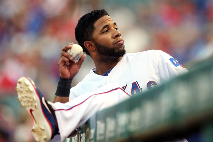 Texas shortstop Elvis Andrus throws a ball to a fan from the dugout before the Minnesota...
