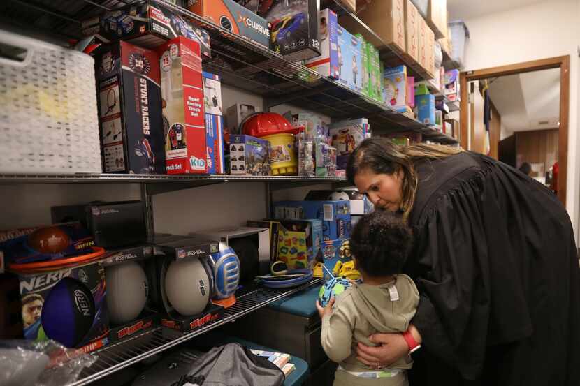A young child receives a toy from Judge Delia Gonzales' stash after a hearing Wednesday in...