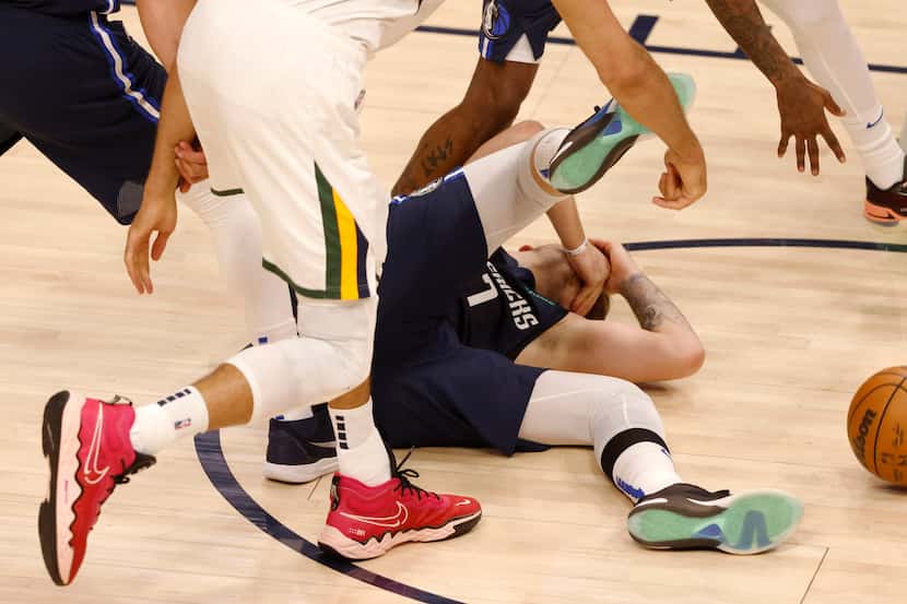 Dallas Mavericks guard Luka Doncic (77) falls after getting hit in the face by Utah Jazz...