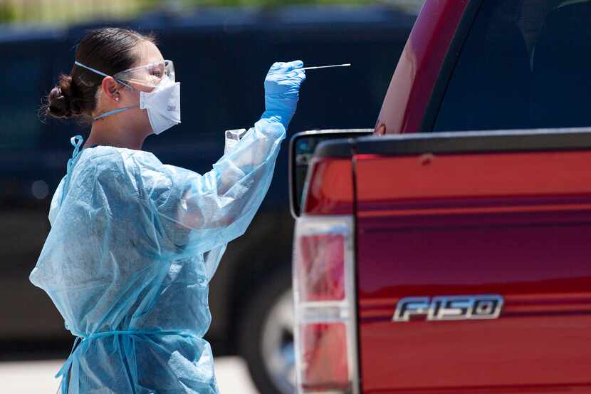 A medical worker conducts a COVID19 test on a passenger during the FEMA mobile drive-through...