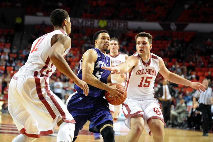 TCU guard Kyan Anderson (5) drives to the basket while being defended by Oklahoma Sooners...