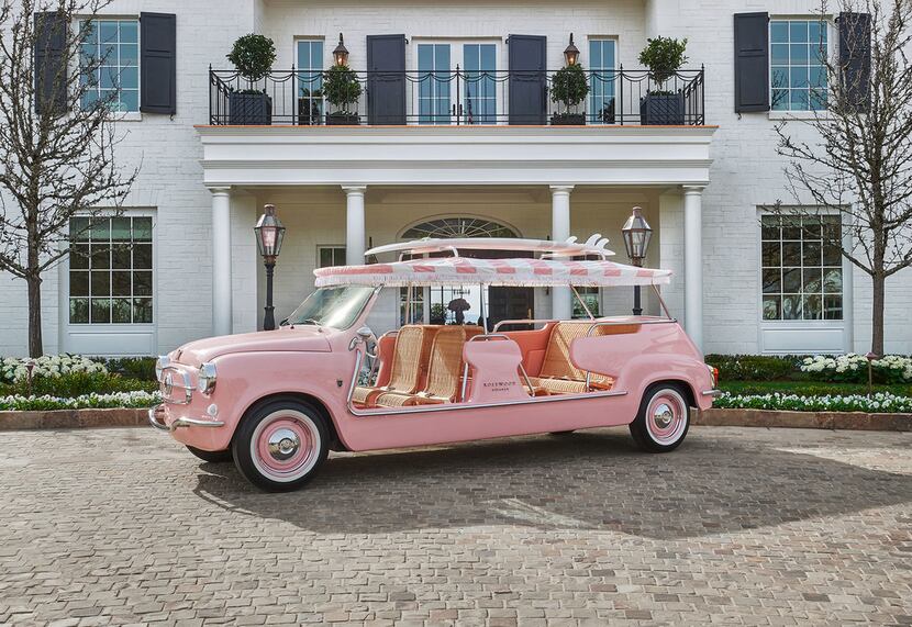 Rosewood Miramar Beach totes guests around in a pink vehicle topped with a surfboard.