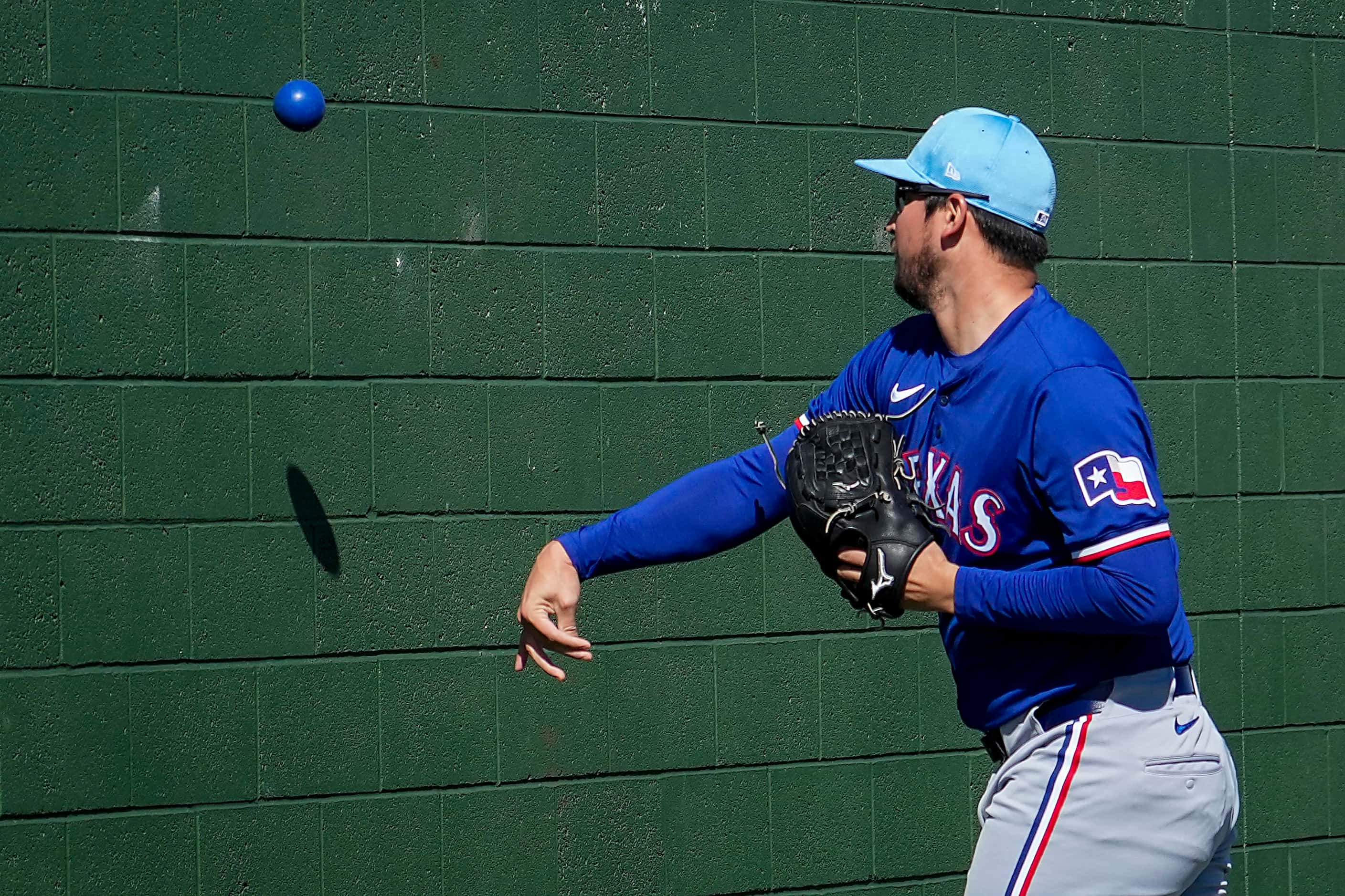 Texas Rangers pitcher Dane Dunning tosses a weighted ball against a bullpen wall during a...