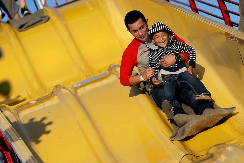 Jaime Flores and his son Jamie Flores Jr., 3, slide down the "Super Slide" during the Main...