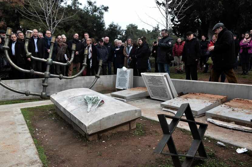 People gather to protest at the desecrated Jewish Memorial Cemetery vandalized two days...