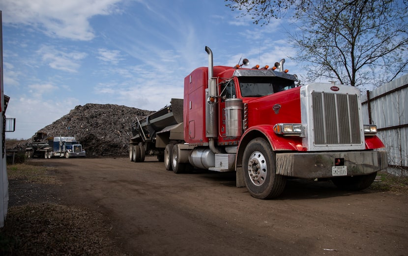 Trucks haul off shingles from the mountain of roofing shingles at "Shingle Mountain" at Blue...